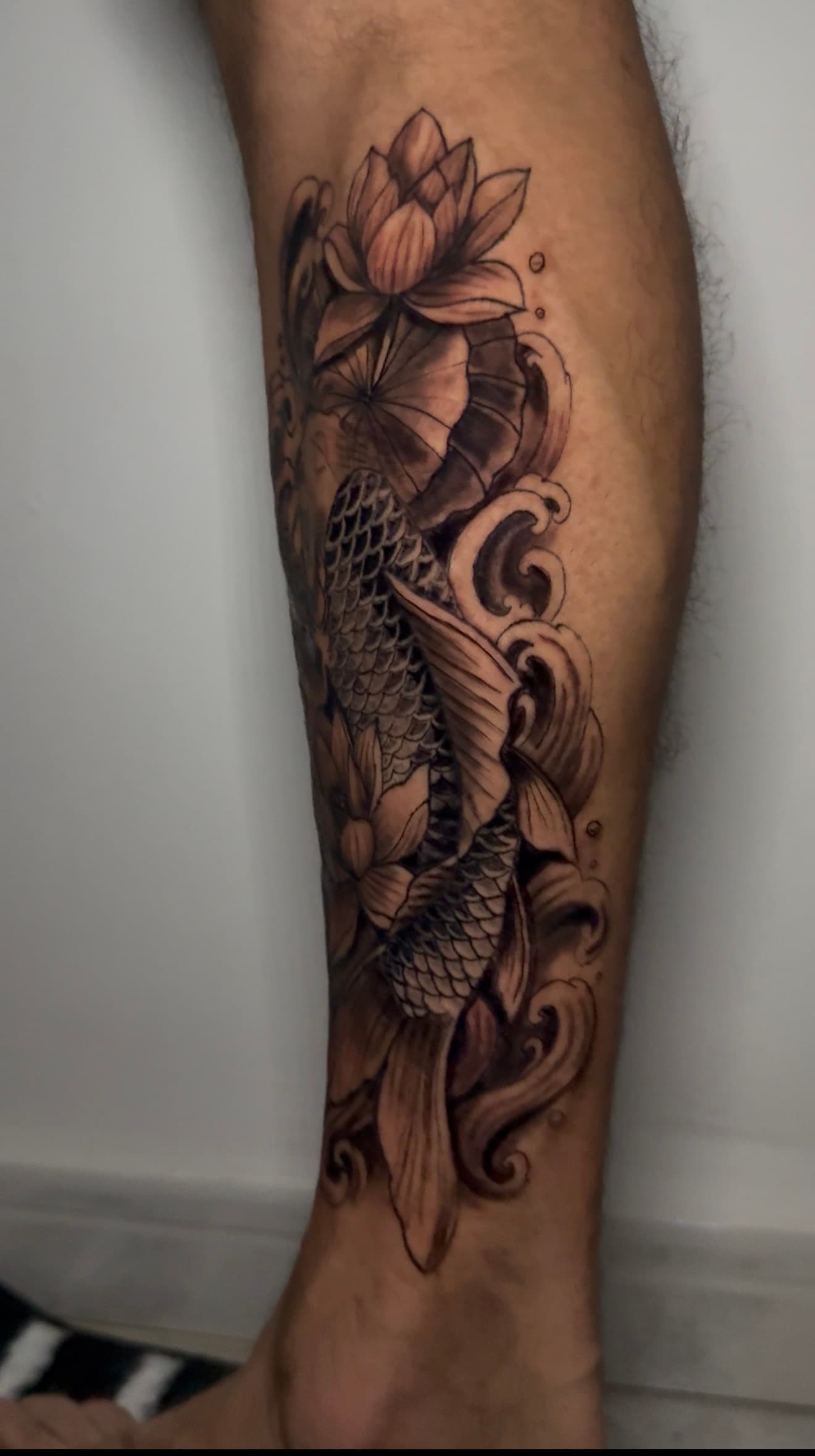 Tatuaje vertical de carpa koi ascendente con loto, black & grey japonés.